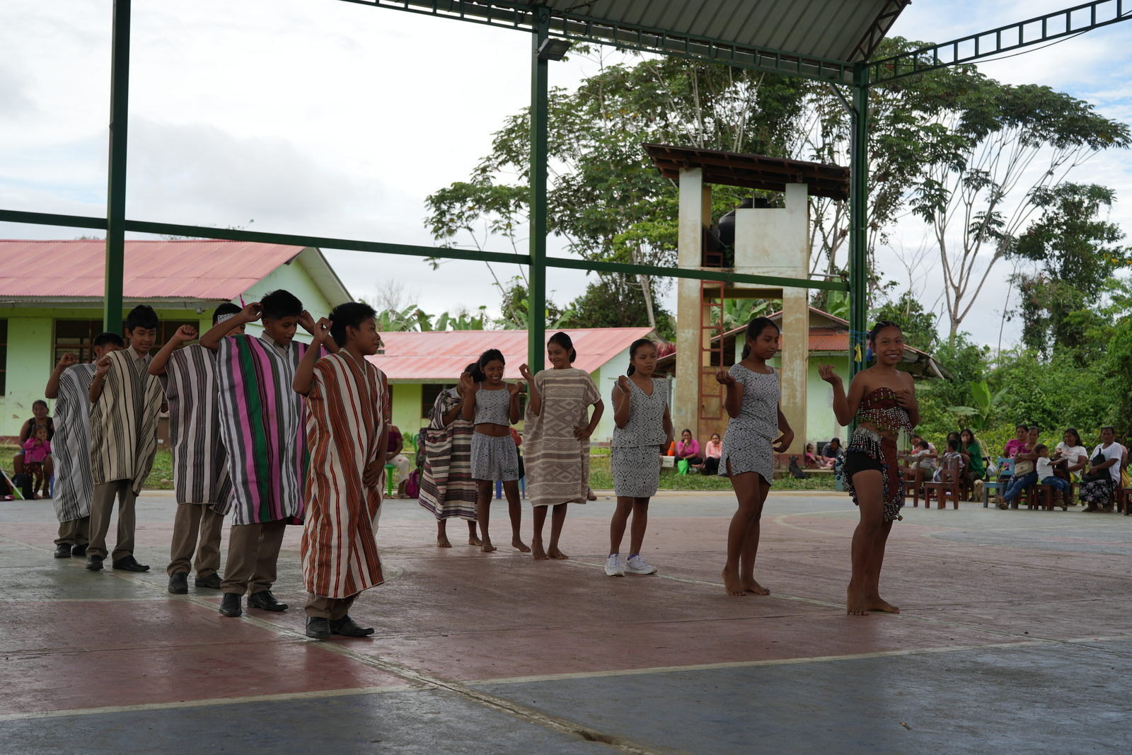 Estudiantes con cushmas matsigenkas durante una danza en la losa de la comunidad.